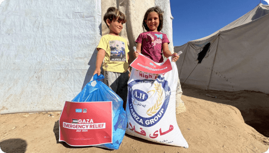 Two children in Gaza holding Muntada Aid emergency relief parcels