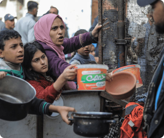 A family in Gaza queuing for food aid with cooking pots